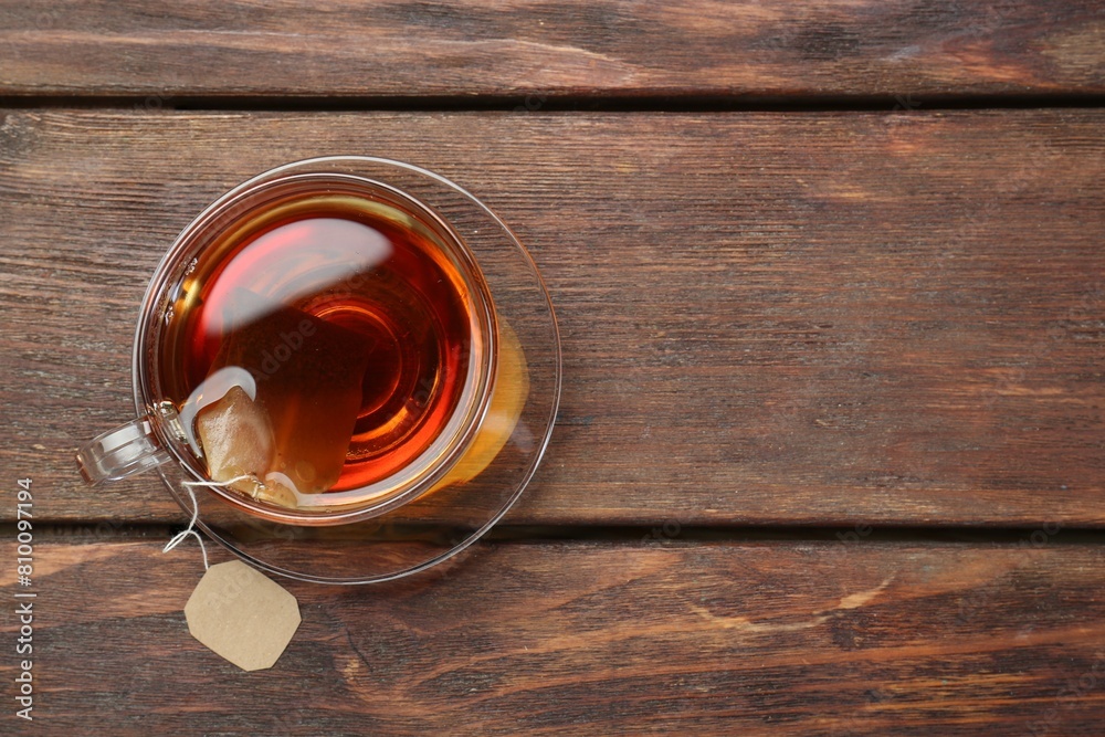 Brewing aromatic tea. Cup with teabag on wooden table, top view. Space for text Brewing aromatic tea. Cup with teabag on wooden table, top view. Space for text