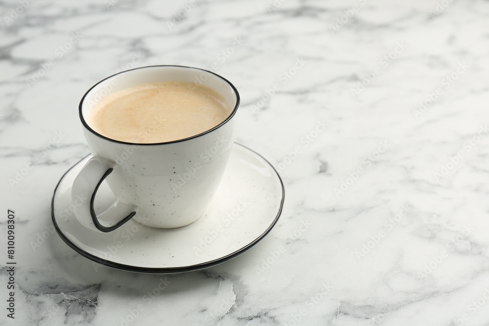 Tasty cappuccino in cup and saucer on white marble table, closeup. Space for text Tasty cappuccino in cup and saucer on white marble table, closeup. Space for text