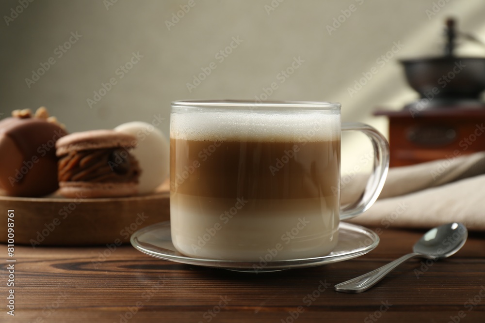 Aromatic coffee in cup, macarons and spoon on wooden table, closeup Aromatic coffee in cup, macarons and spoon on wooden table, closeup