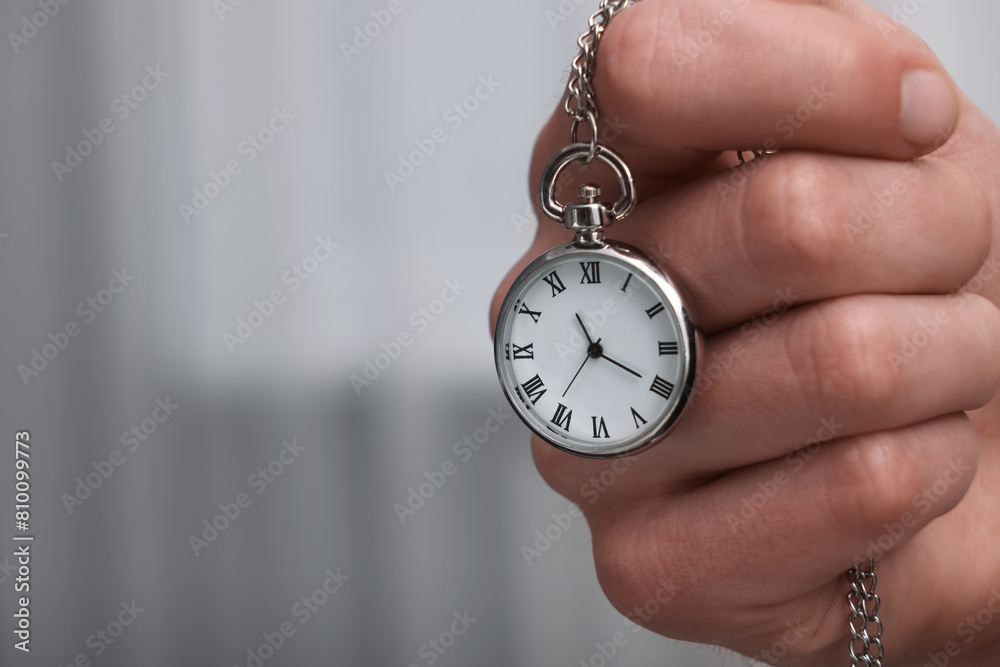 Man holding chain with elegant pocket watch, closeup. Space for text Man holding chain with elegant pocket watch, closeup. Space for text