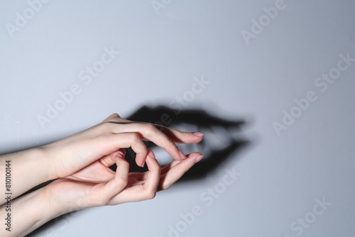 Shadow puppet. Woman making hand gesture like crocodile on grey background, closeup. Space for text
