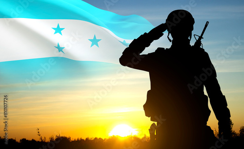 Silhouette of a saluting soldier with Honduras flag against the sunset