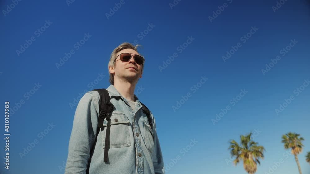 A man with a backpack walks past a building with surfer hair