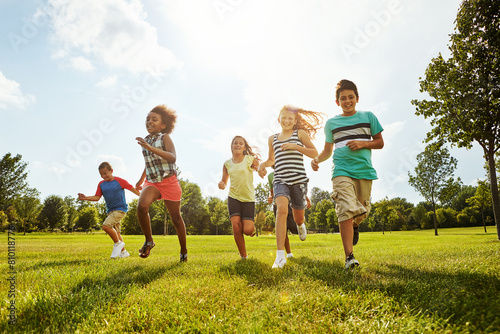 Happy kids, diversity and running with friends in nature for fun, playful day or summer at park. Group of excited children or youth enjoying sunny outdoor holiday or weekend on grass field together photo