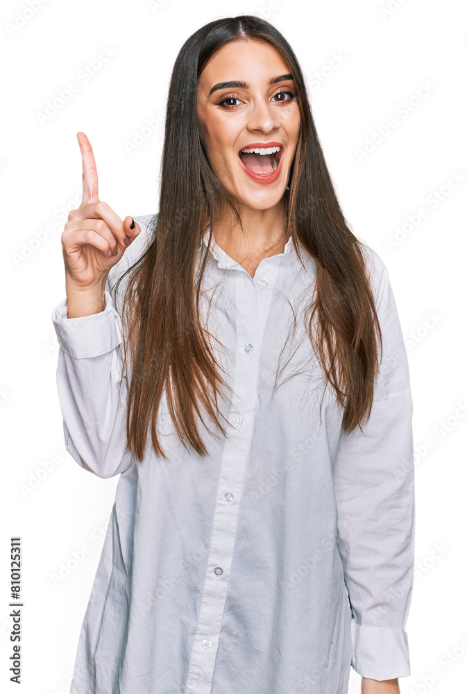 Young beautiful woman wearing casual white shirt pointing finger up with successful idea. exited and happy. number one. Young beautiful woman wearing casual white shirt pointing finger up with successful idea. exited and happy. number one.