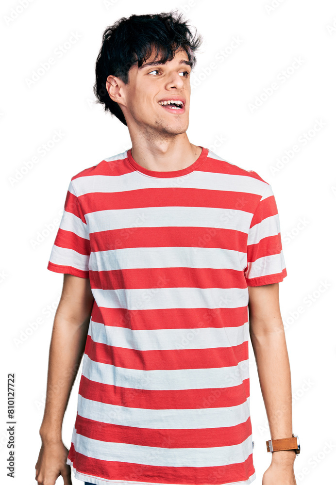 Handsome hipster young man wearing casual striped t shirt looking away to side with smile on face, natural expression. laughing confident. Handsome hipster young man wearing casual striped t shirt looking away to side with smile on face, natural expression. laughing confident.