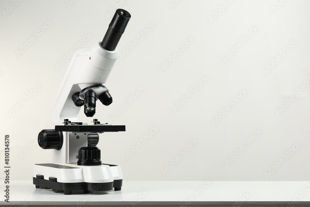 Modern microscope on white table, space for text