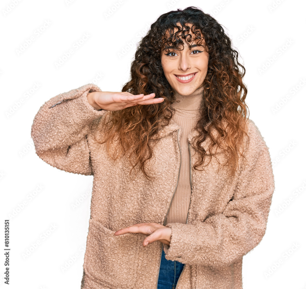 Young hispanic girl wearing winter clothes gesturing with hands showing big and large size sign, measure symbol. smiling looking at the camera. measuring concept. Young hispanic girl wearing winter clothes gesturing with hands showing big and large size sign, measure symbol. smiling looking at the camera. measuring concept.