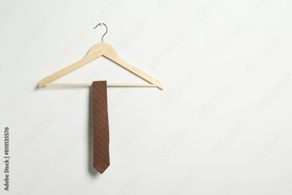 Fototapeta premium Hanger with striped necktie on white wall. Space for text