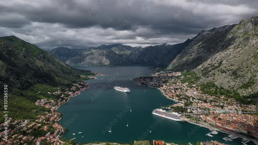 Kotor bay in Montenegro, aerial view timelapse. Cloudy summer day with a cruise ship in the sea. Traffic in the sea. Mountains around the bay and Kotor old town. Kotor bay in Montenegro, aerial view timelapse. Cloudy summer day with a cruise ship in the sea. Traffic in the sea. Mountains around the bay and Kotor old town.