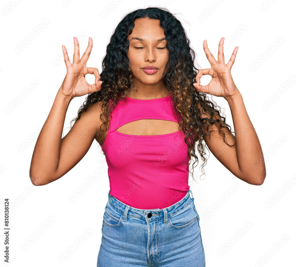 Young hispanic woman with curly hair wearing pink top relax and smiling with eyes closed doing meditation gesture with fingers. yoga concept. Young hispanic woman with curly hair wearing pink top relax and smiling with eyes closed doing meditation gesture with fingers. yoga concept.