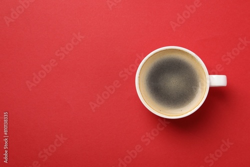 Aromatic coffee in cup on red background, top view. Space for text