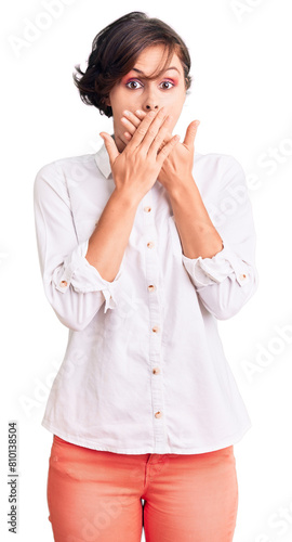 Beautiful young woman with short hair wearing elegant white shirt shocked covering mouth with hands for mistake. secret concept.