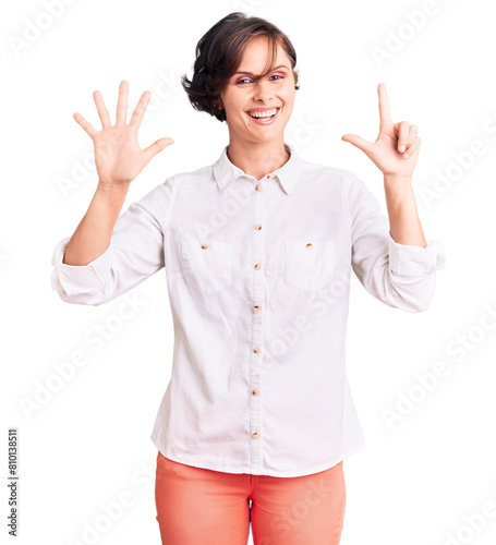 Beautiful young woman with short hair wearing elegant white shirt showing and pointing up with fingers number seven while smiling confident and happy.