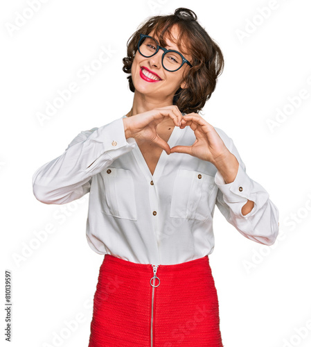 Young hispanic woman wearing business style and glasses smiling in love doing heart symbol shape with hands. romantic concept.