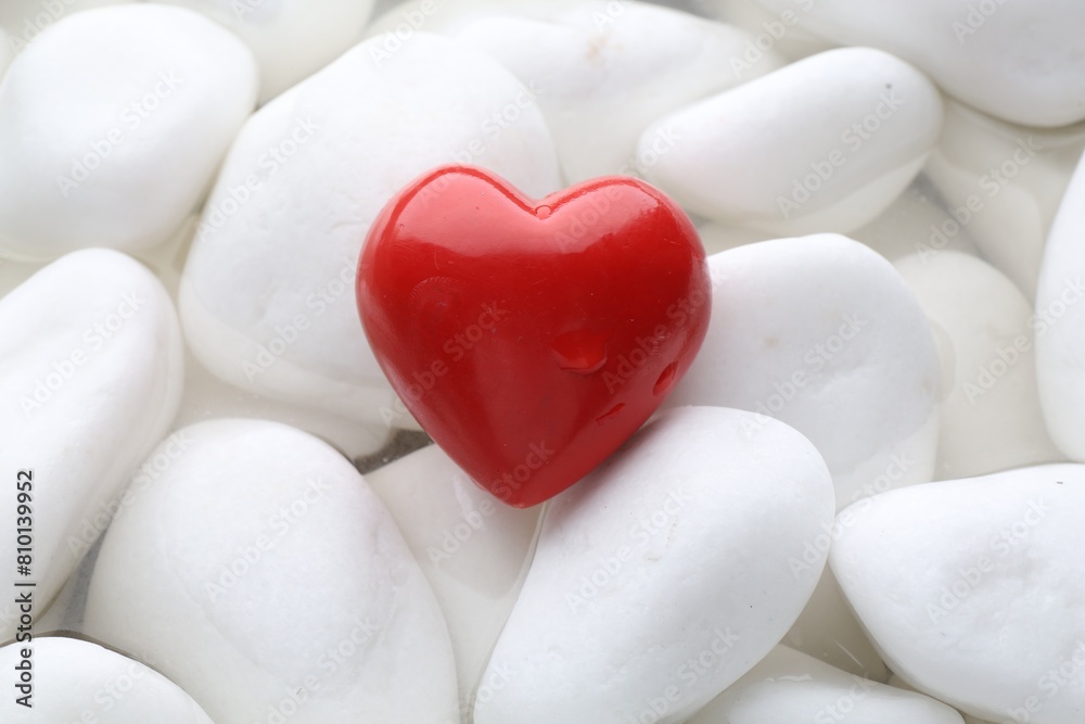 Obraz premium Red decorative heart on stones and water, top view