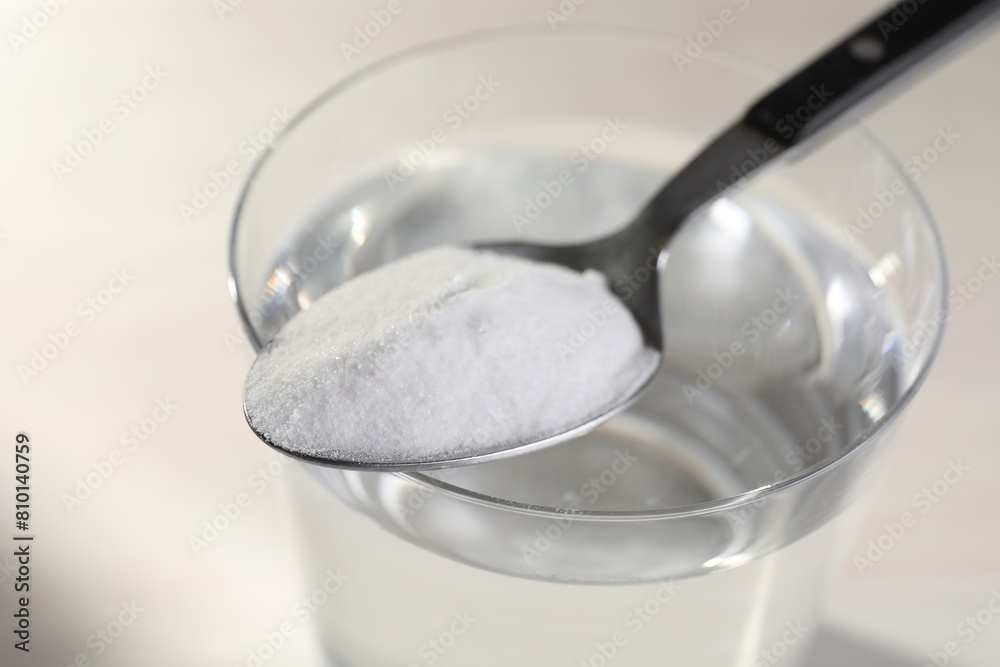Glass of water and spoon with baking soda on light background, closeup Glass of water and spoon with baking soda on light background, closeup