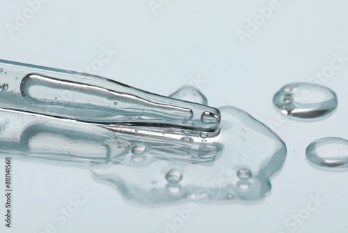 Glass pipette and transparent liquid on light background  closeup