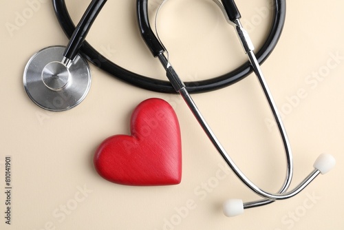 Stethoscope and red heart on beige background, top view