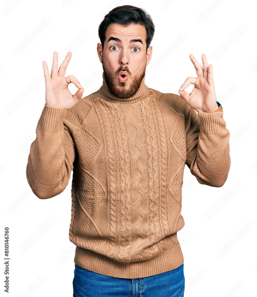 Naklejka premium Young hispanic man wearing casual clothes looking surprised and shocked doing ok approval symbol with fingers. crazy expression