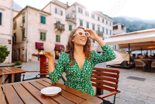 Woman in outdoors street coffee shop cafe sitting at table with cup of coffee, relaxing in restaurant on free time. People, fashion, lifestyle, travel and vacations concept © maxbelchenko