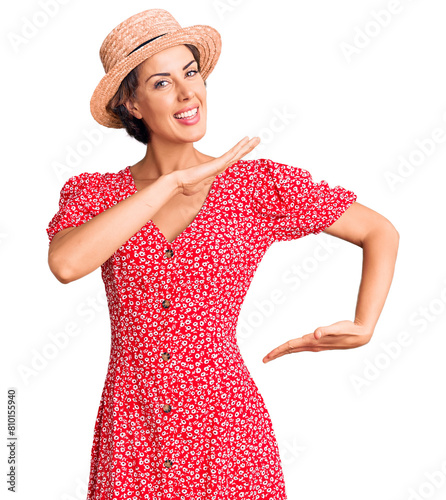 Фотография Young beautiful woman wearing summer hat gesturing with hands showing big and large size sign, measure symbol