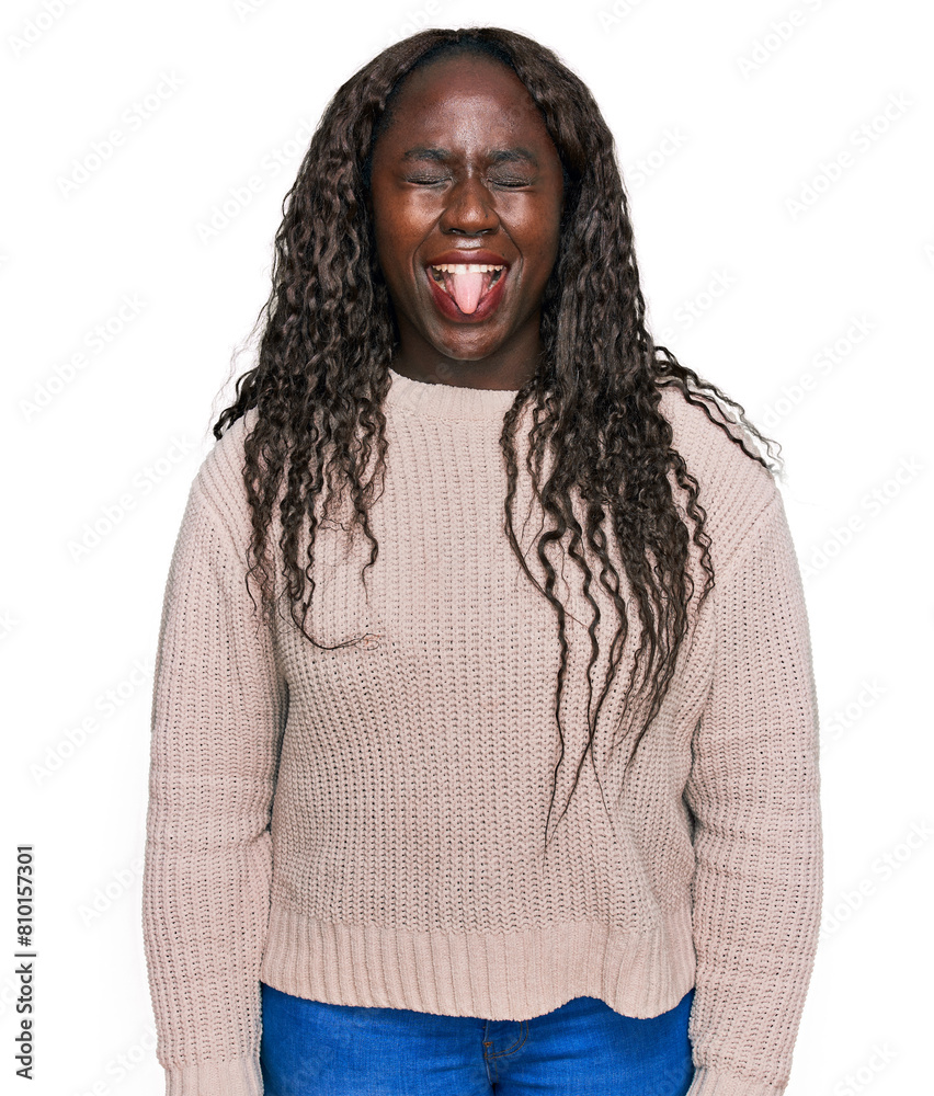 Young african woman wearing wool winter sweater sticking tongue out happy with funny expression. emotion concept. Young african woman wearing wool winter sweater sticking tongue out happy with funny expression. emotion concept.