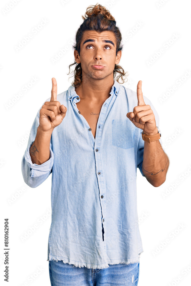 Young hispanic man wearing summer style pointing up looking sad and upset, indicating direction with fingers, unhappy and depressed. Young hispanic man wearing summer style pointing up looking sad and upset, indicating direction with fingers, unhappy and depressed.
