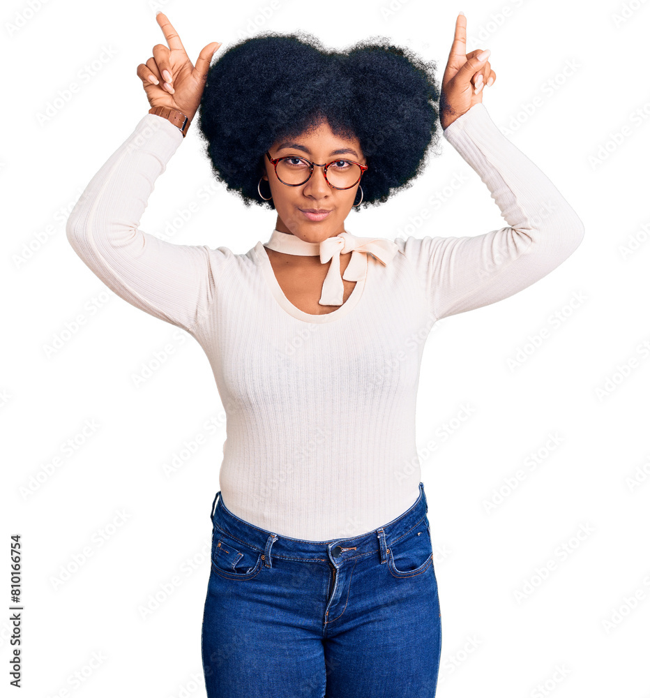 Young african american girl wearing casual clothes and glasses doing funny gesture with finger over head as bull horns Young african american girl wearing casual clothes and glasses doing funny gesture with finger over head as bull horns
