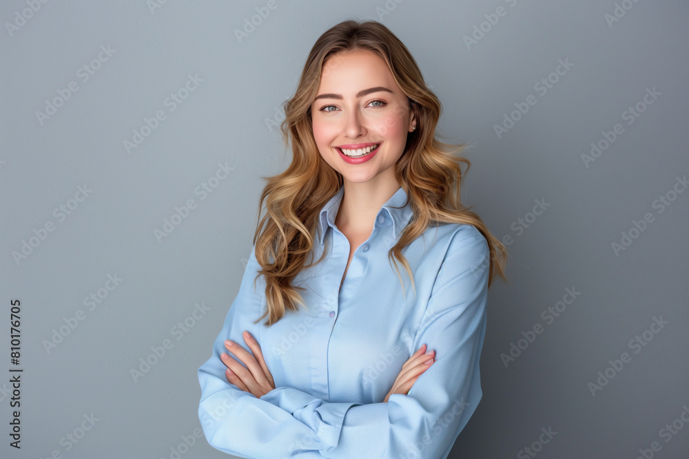 With a smile on her face, a confident young businesswoman in a blue shirt looks into the camera, presenting her professionalism and charisma, standing with her arms crossed against a gray background. With a smile on her face, a confident young businesswoman in a blue shirt looks into the camera, presenting her professionalism and charisma, standing with her arms crossed against a gray background.