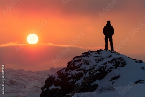 Lone silhouette standing proudly snow-capped outlined hues setting sun