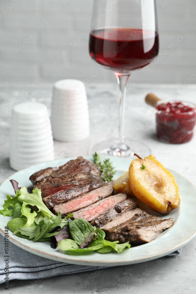 Delicious roasted beef meat, caramelized pear and greens served on light table