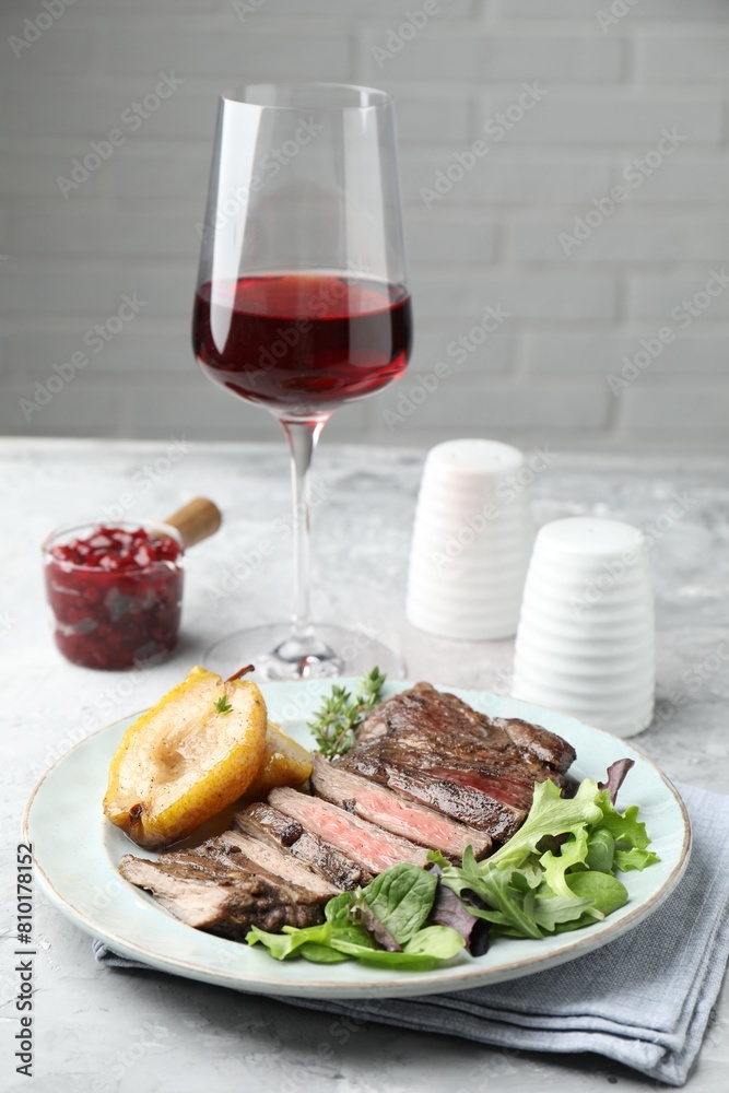 Delicious roasted beef meat, caramelized pear and greens served on light table Delicious roasted beef meat, caramelized pear and greens served on light table