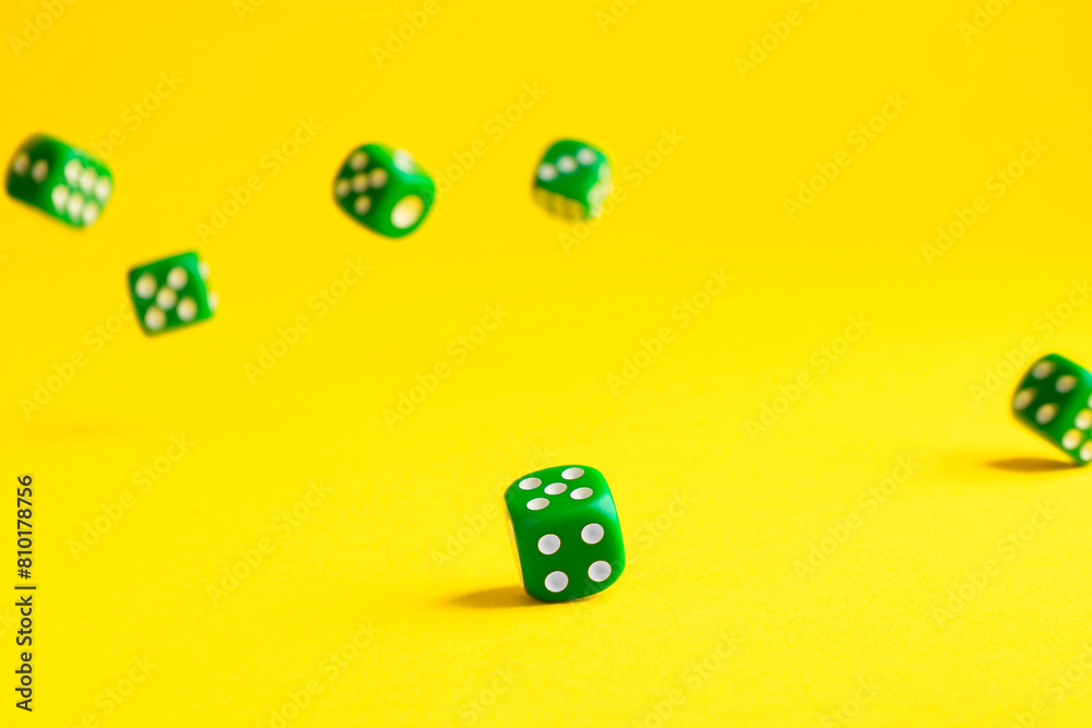 Many green game dices falling on yellow background Many green game dices falling on yellow background