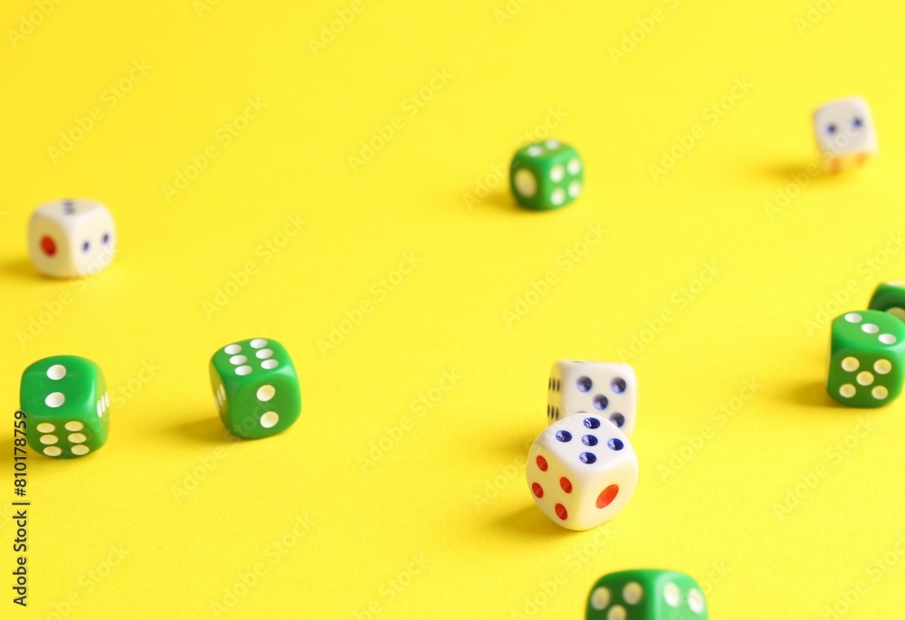Many color game dices falling on yellow background Many color game dices falling on yellow background