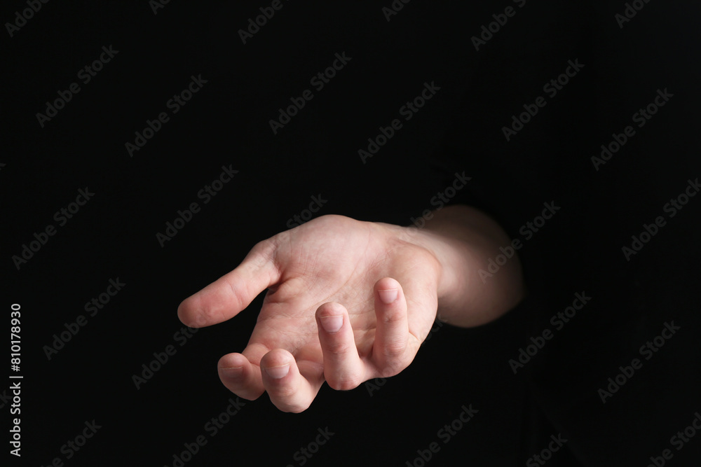 Man holding something in his hand on black background, closeup Man holding something in his hand on black background, closeup