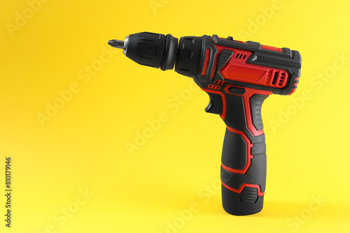 Modern electric screwdriver on yellow background. Space for text