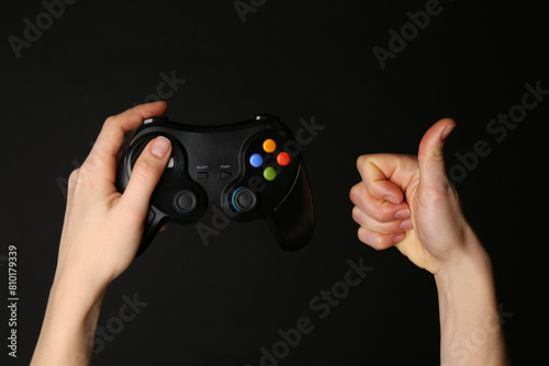 Wallpaper Mural Woman with game controller showing thumbs up on black background, closeup Torontodigital.ca