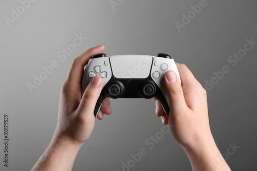 Woman using wireless game controller on grey background, closeup