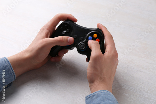 Man using wireless game controller at white table, closeup