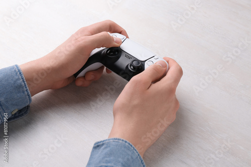 Man using wireless game controller at white table, closeup © New Africa