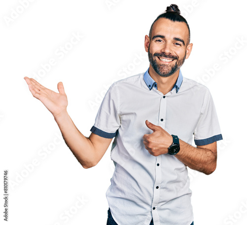 Hispanic man with ponytail wearing casual white shirt showing palm hand and doing ok gesture with thumbs up, smiling happy and cheerful