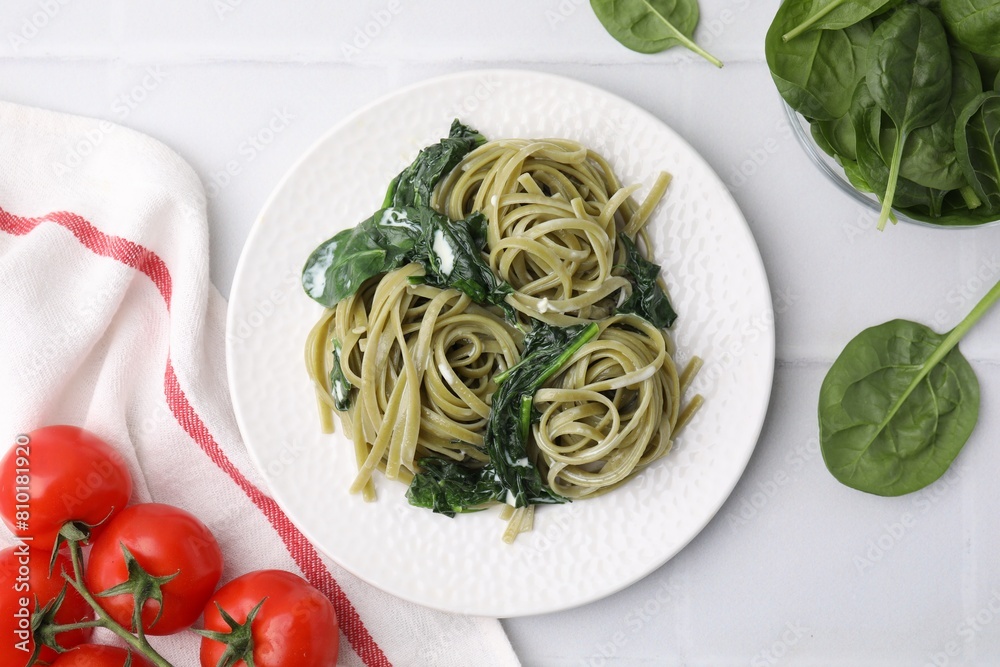 Tasty pasta with spinach, sauce and tomatoes on white tiled table, flat lay Tasty pasta with spinach, sauce and tomatoes on white tiled table, flat lay