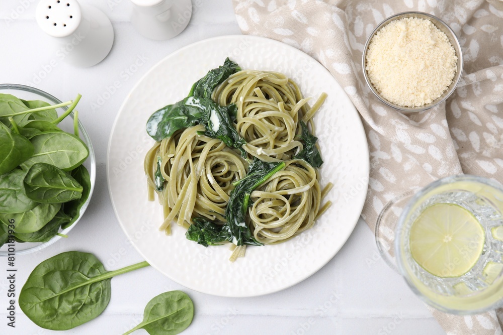 Tasty pasta with spinach and sauce served on white tiled table, flat lay Tasty pasta with spinach and sauce served on white tiled table, flat lay