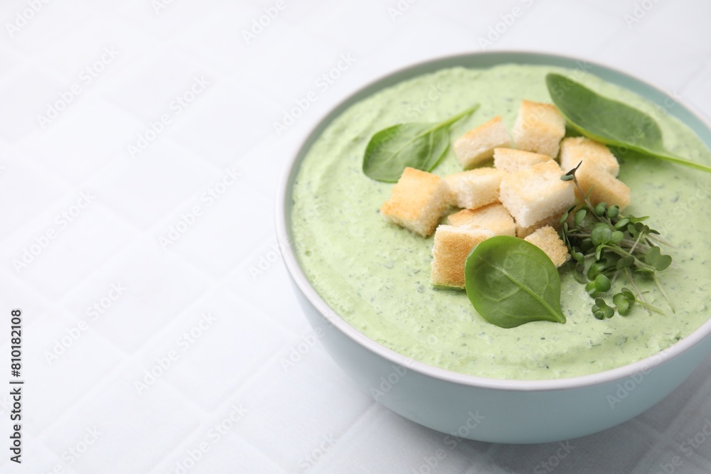 Delicious spinach cream soup with croutons in bowl on white tiled table. Space for text Delicious spinach cream soup with croutons in bowl on white tiled table. Space for text