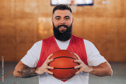 Portrait of a smiling caucasian bearded basketball player holding a ball