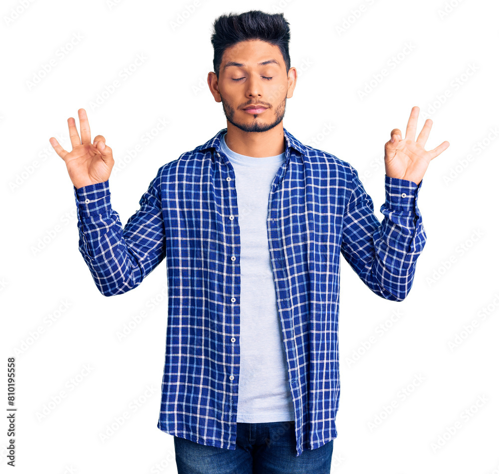 Handsome latin american young man wearing casual shirt relax and smiling with eyes closed doing meditation gesture with fingers. yoga concept. Handsome latin american young man wearing casual shirt relax and smiling with eyes closed doing meditation gesture with fingers. yoga concept.