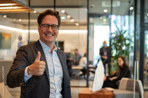 A professional man giving a thumbs-up to his colleagues in a modern office space