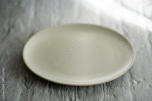 A white plate sits on a grey surface