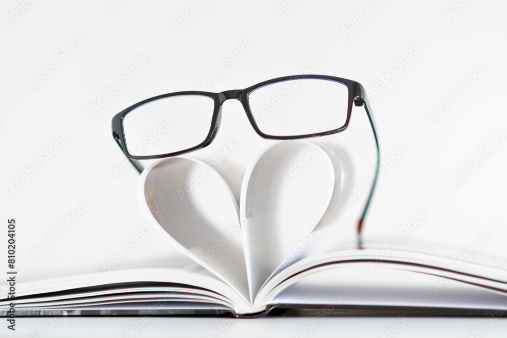 A pair of glasses is placed on top of a heart-shaped paper A pair of glasses is placed on top of a heart-shaped paper